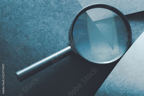 magnifying glass. comparison assessment and analysis. loupe on layered blue paper background. photo