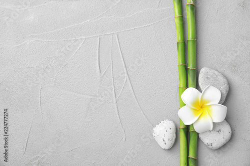 Composition with bamboo branches, stones and plumeria on light background, top view. Space for text