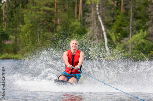 Fototapeta Naklejka Na Ścianę i Meble -  Young athletic man riding kneeboard on a lake