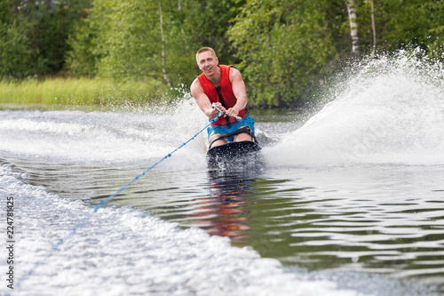 Young athletic man riding kneeboard on a lake