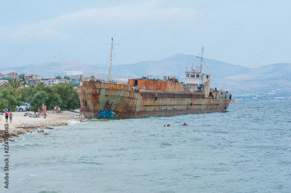 Shipwreck on a beach. Tourists swimming. Adriatic Sea.