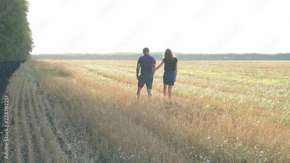 young loving couple in nature in summer on a background of field with oats, there is noise on the video young loving couple in nature in summer on a background of field with oats, there is noise on the video