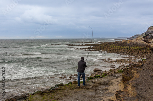 Man Fishing Alone in the Shore, in a Cold Day
