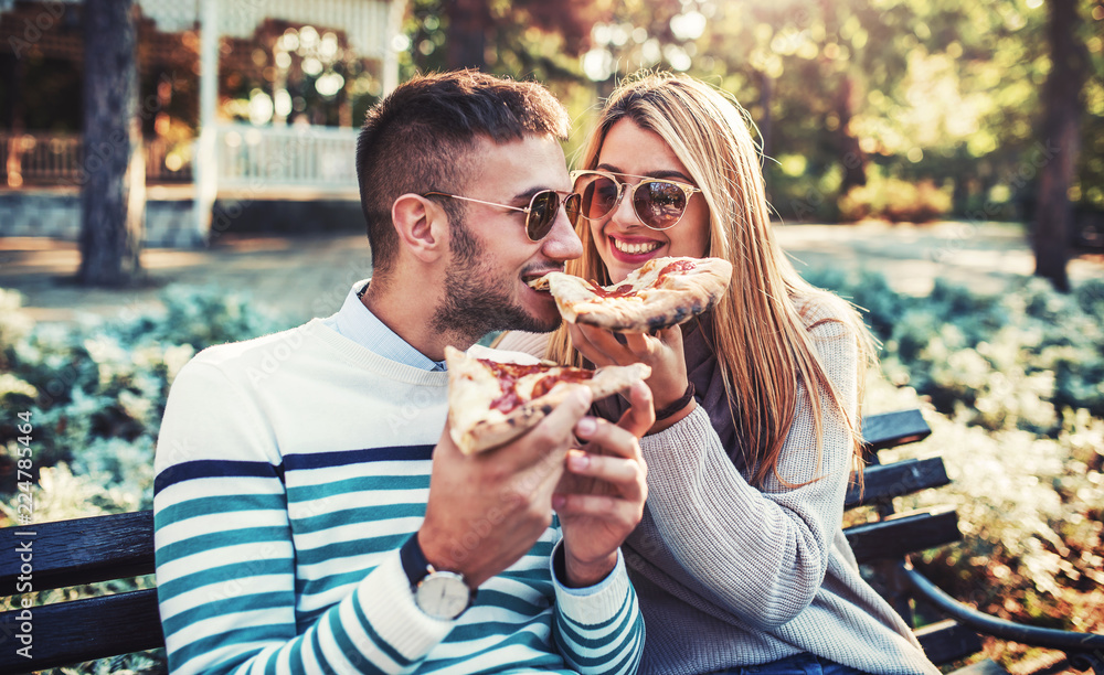 Couple eating pizza outdoors. Dating, consumerism, food, lifestyle concept Couple eating pizza outdoors. Dating, consumerism, food, lifestyle concept