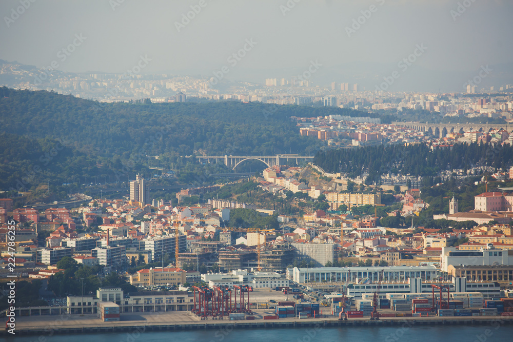 Beautiful super wide-angle panoramic aerial view of Lisbon, Portugal with harbor and skyline scenery beyond the city, shot from belvedere observation deck of Cristo Rei