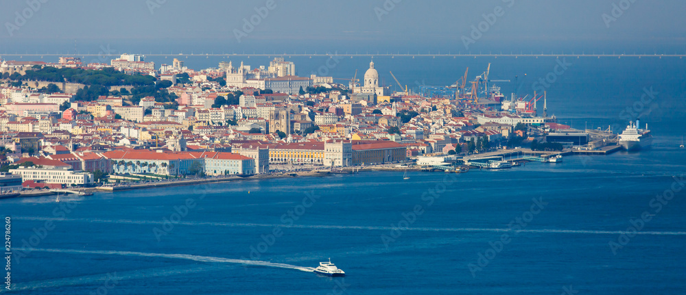 Obraz premium Beautiful super wide-angle panoramic aerial view of Lisbon, Portugal with harbor and skyline scenery beyond the city, shot from belvedere observation deck of Cristo Rei