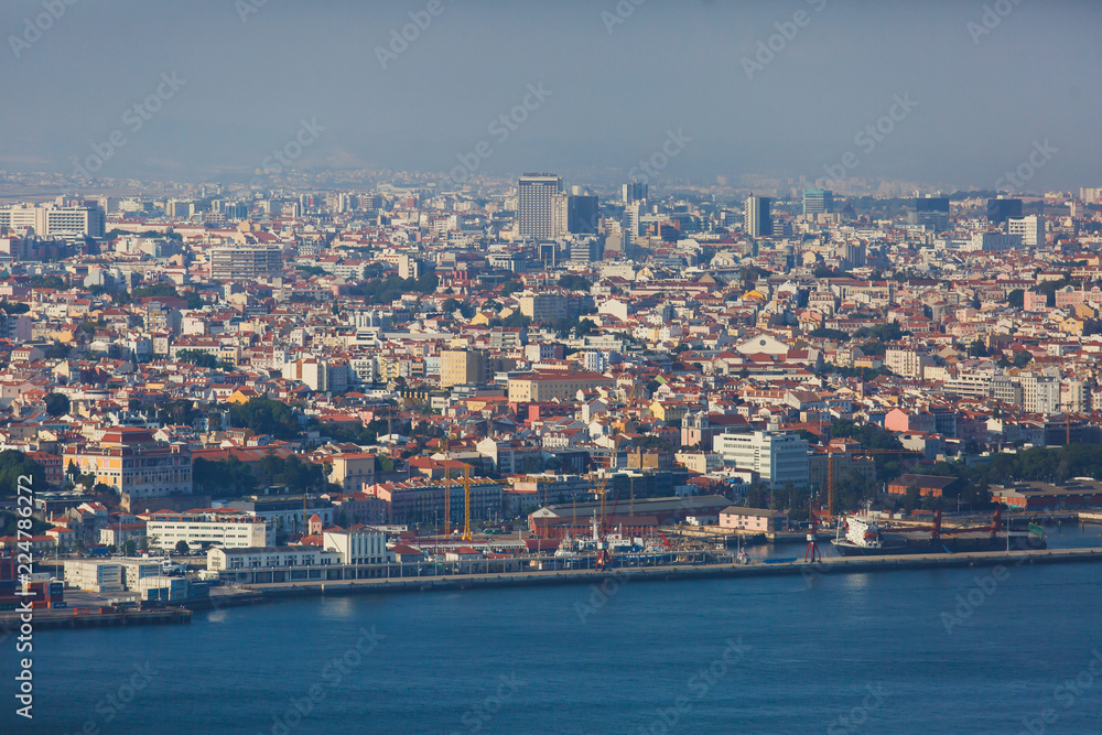 Beautiful super wide-angle panoramic aerial view of Lisbon, Portugal with harbor and skyline scenery beyond the city, shot from belvedere observation deck of Cristo Rei