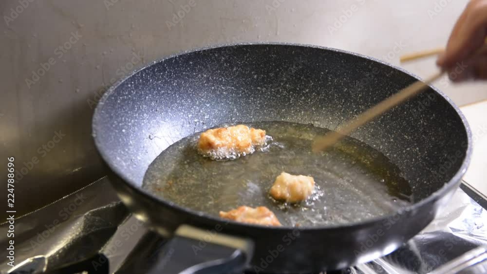 breaded chicken pieces being deep fried in a cast iron pan breaded chicken pieces being deep fried in a cast iron pan