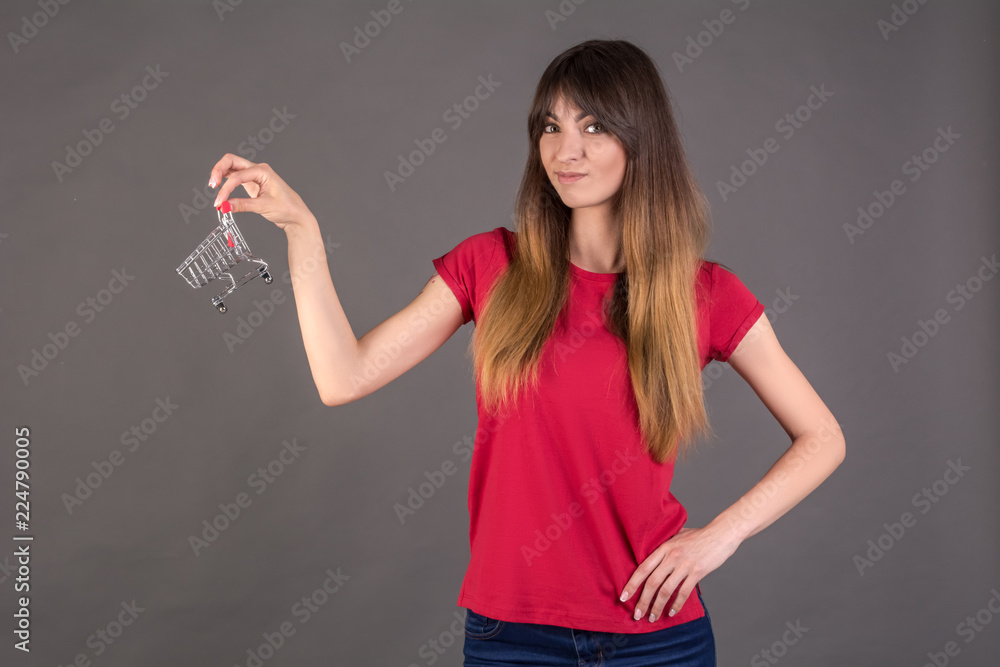 A girl in a red T-shirt with a shopping trolley. Woman does not like to go shopping. A girl in a red T-shirt with a shopping trolley. Woman does not like to go shopping.