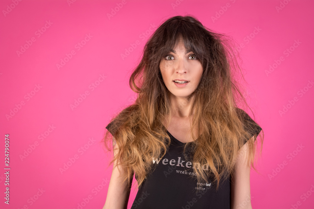 Girl with disheveled hair on a pink background. Creative concept on the problem of styling Girl with disheveled hair on a pink background. Creative concept on the problem of styling