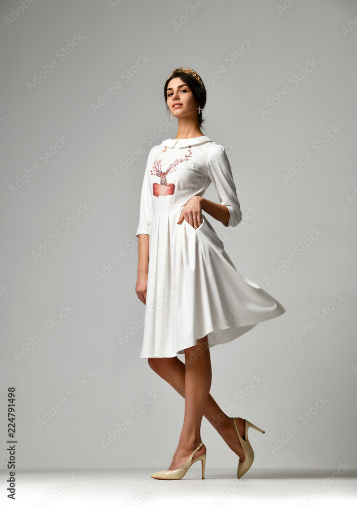eautiful woman walking in new white pattern casual office dress on grey background eautiful woman walking in new white pattern casual office dress on grey background