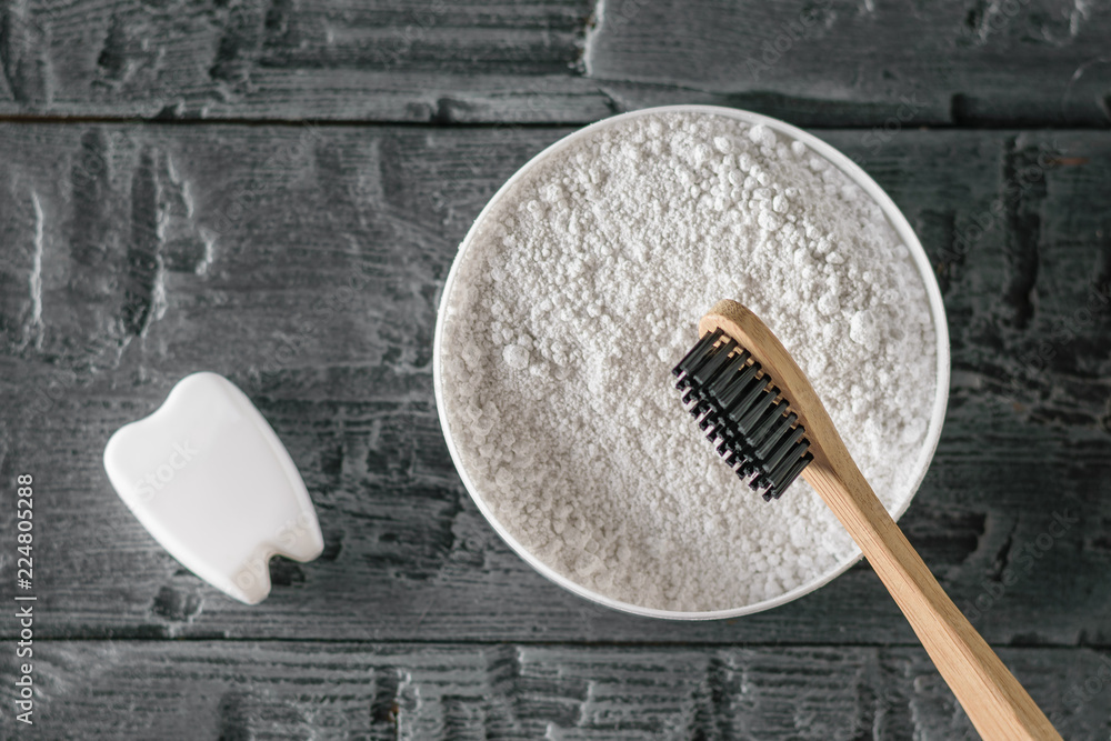 Tooth powder, wooden toothbrush and tooth figurine on black wooden table. The view from the top. Flat lay. Tooth powder, wooden toothbrush and tooth figurine on black wooden table. The view from the top. Flat lay.