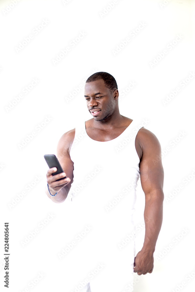 Fototapeta premium Black man is standing closed to white wall with mobile phone