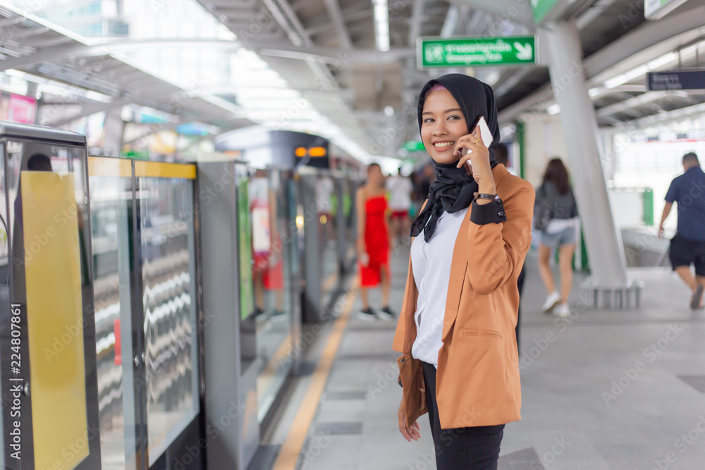young muslim woman using telephone on skytrain station.