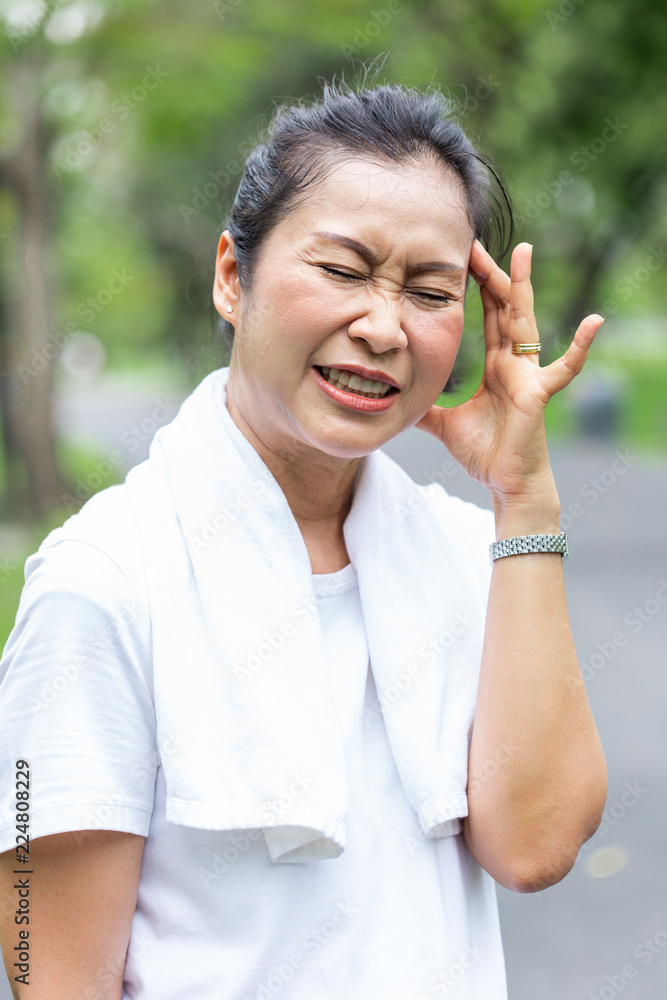 asian senior women wear white shirt having headache after exercise. asian senior women wear white shirt having headache after exercise.