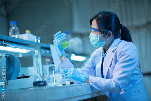 Young female scientist or researcher in medical lab with test tube centrifuge and flask