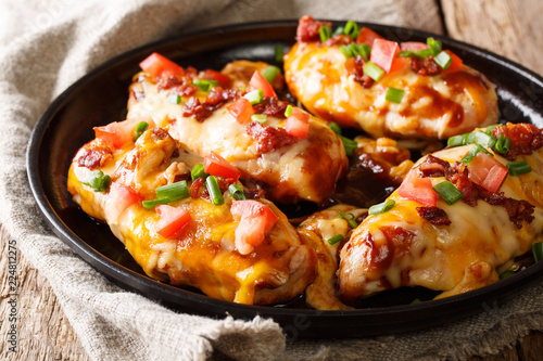 Chicken breast baked with monterey cheese and cheddar, bacon, tomatoes and barbecue sauce close-up. horizontal photo