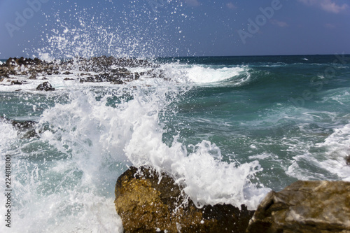 sea waves with foam breaking on the stones of the coastline, splashes of water flying around
