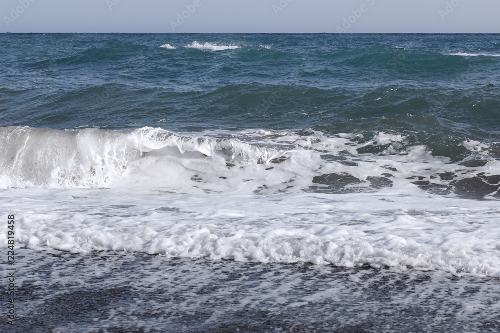 Fototapeta premium white splashes of waves in the sea rolling on the sandy shore