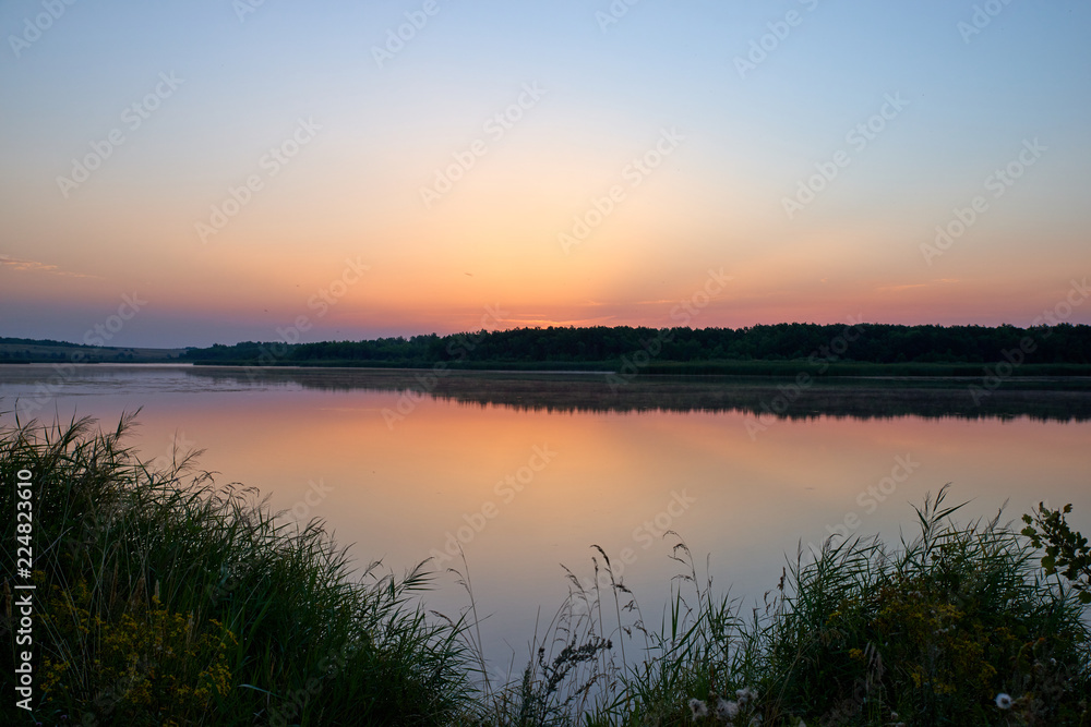 Landscape of the dawn sky and reflection in the lake. Warm colors and bright colors