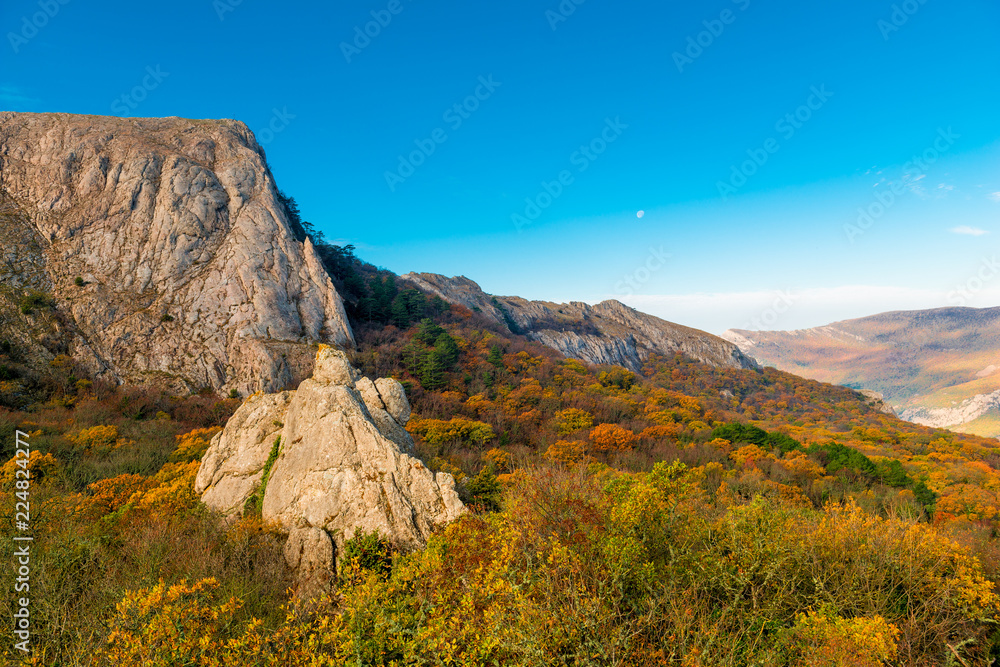 Landscape of the Crimea in the autumn sunny day- mountains, a busy bright forest and blue sky