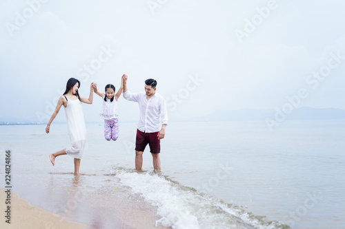 Family on the beach.happy family holiday travel summer.father,mother and daugter are walking hand in hand to walk the sea on the beach