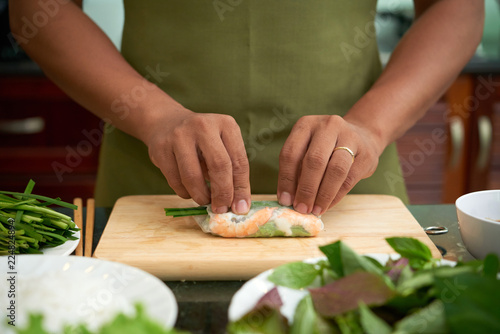 Man making traditional Asian spring rolls with shrimp and vegetables