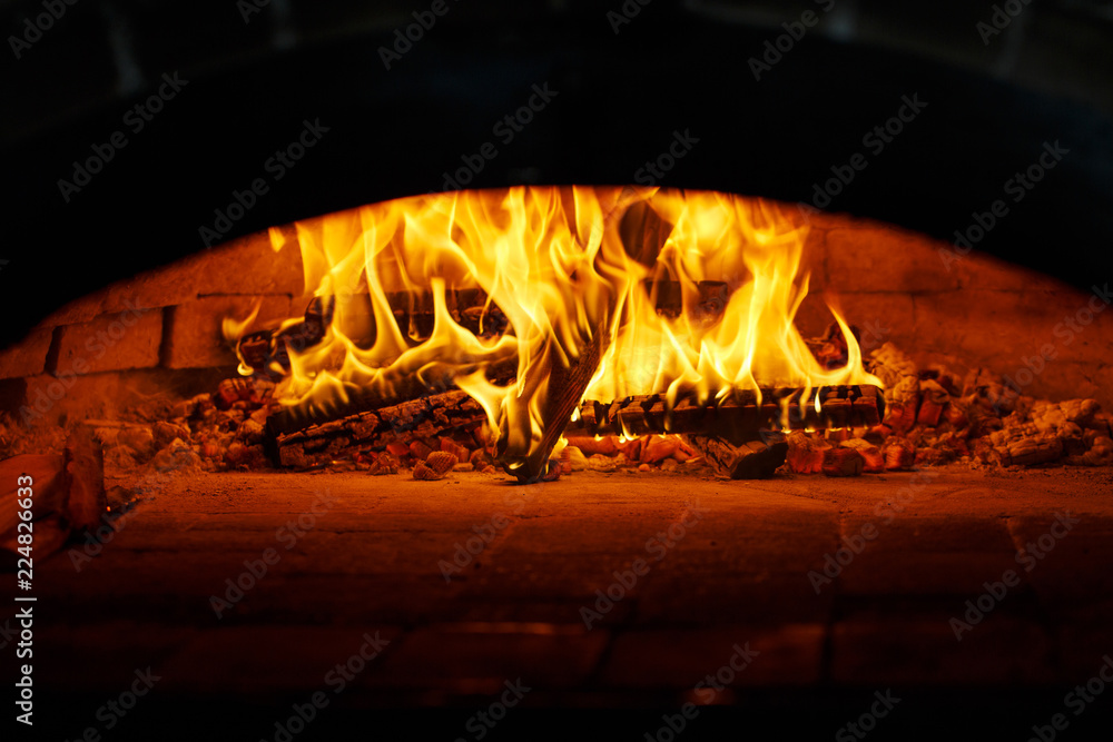 Pizza in the oven. Beautiful fire burns in the furnace. Cooking pizza in the cafe.