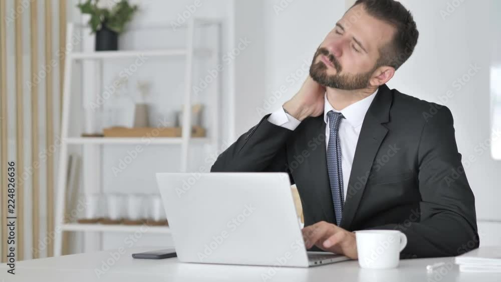 Businessman with Neck Pain working on Laptop Businessman with Neck Pain working on Laptop