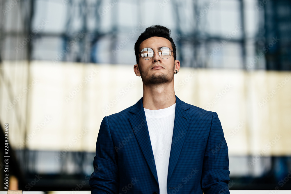 Architect in glasses dressed in stylish clothes stands on the background of a modern glass building Architect in glasses dressed in stylish clothes stands on the background of a modern glass building