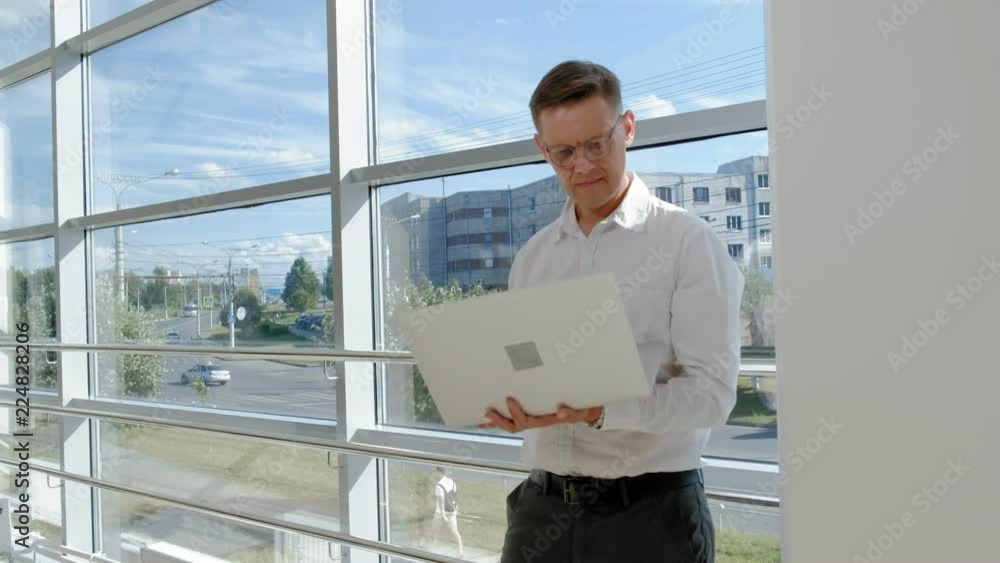 Mature businessman at a window with a laptop Mature businessman at a window with a laptop