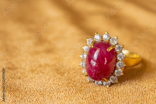 Jewelry red ruby ring on golden fabric background close up