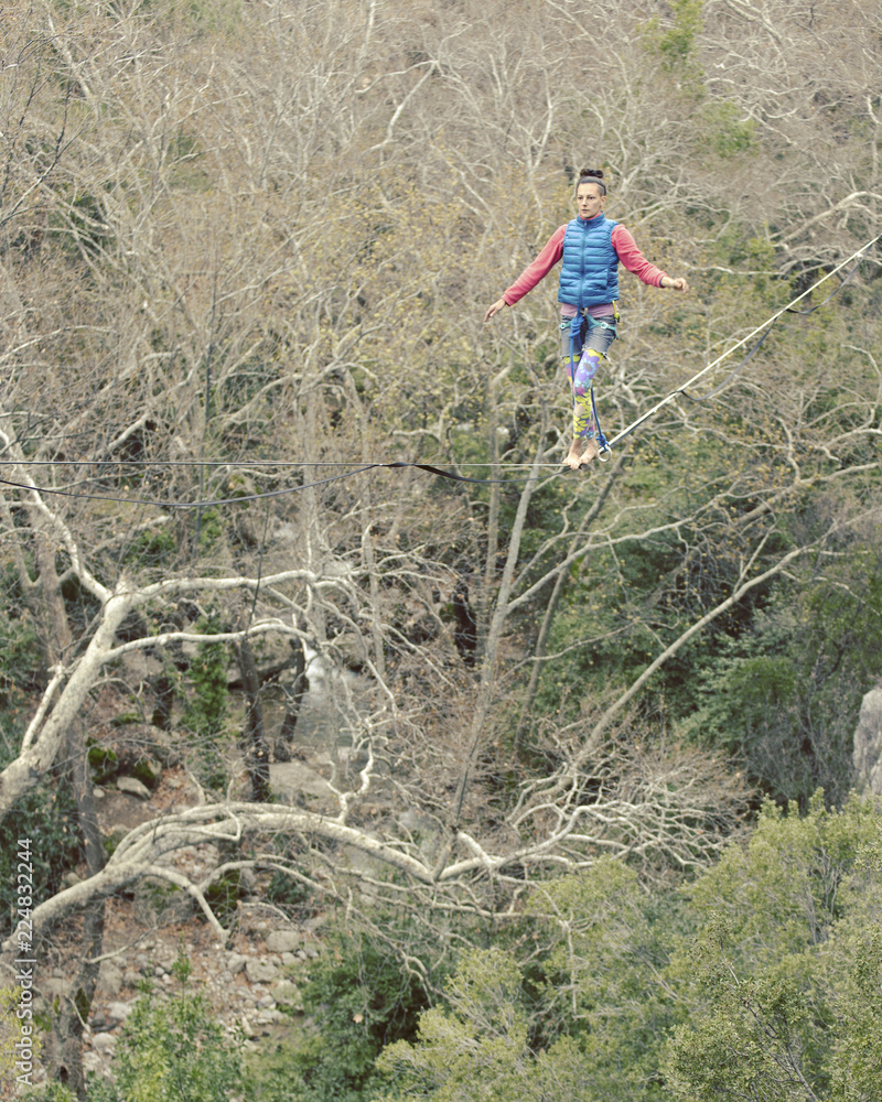 Naklejka premium Highliner on a rope. Highline on a background of mountains. Extreme sport on the nature. Balancing on the sling. Equilibrium at altitude.