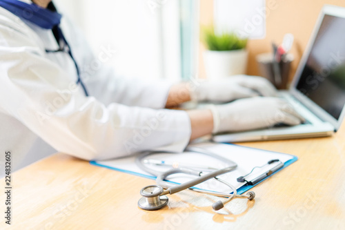 Medical concept.Doctor working with laptop and clipboard, stethoscope on desk.