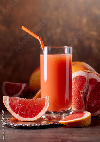 Glass of fresh grapefruit juice and cut fruits . photo