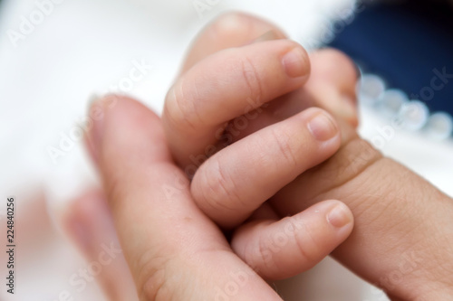 Fingers newborn in the hands of his mother. The tenderness of motherhood is in the details. Procreation in childbirth and love. 
