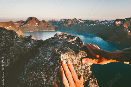 Man hands climbing up to mountain summit travel adventure active lifestyle extreme vacations in Norway