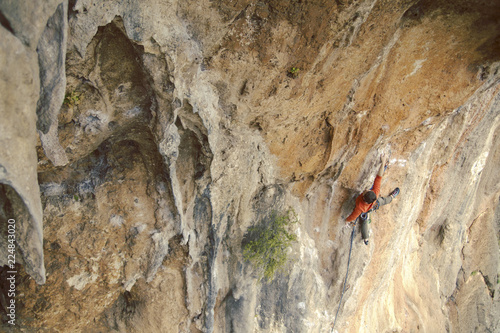 Man rock climber. Rock climber climbs on a rocky wall. Man makes hard move.