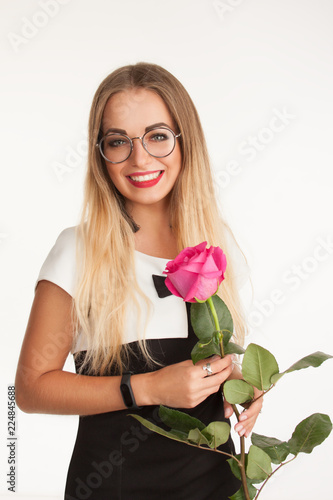 beautiful stylish happy young blonde girl in glasses holding pink rose in studio on white background