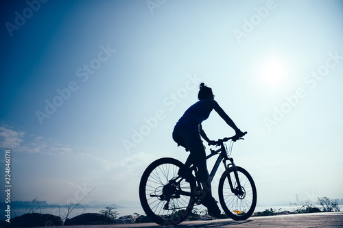 Fototapeta Naklejka Na Ścianę i Meble -  Cycling woman riding mountain mike on sunrise seaside