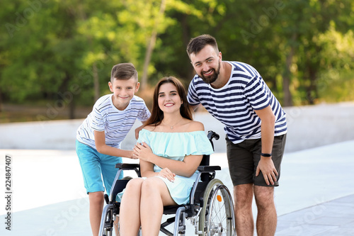 Young woman in wheelchair with her family walking outdoors