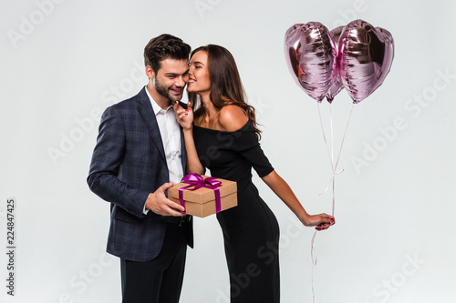 Thank you my love. Young handsome men giving a gift box to his girlfriend while standing against white background photo