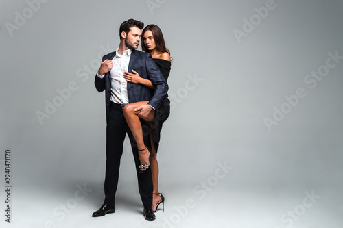 Tell me all your secrets. Full length of young beautiful couple bonding and looking at camera while standing against white background