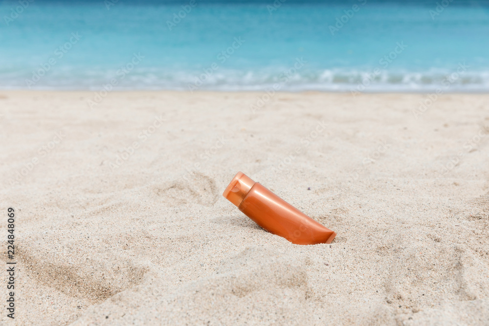 Sunscreen sunblock spf cream on the sea beach sand summer tropical holiday concept