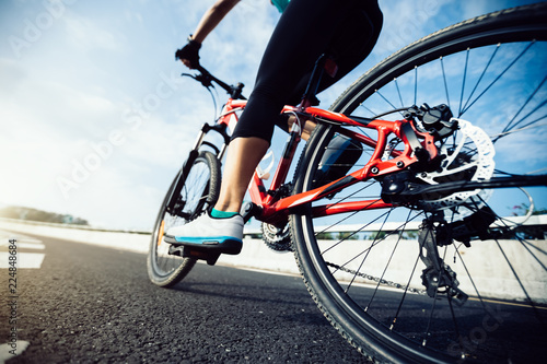 Woman cyclist legs riding Mountain Bike on highway