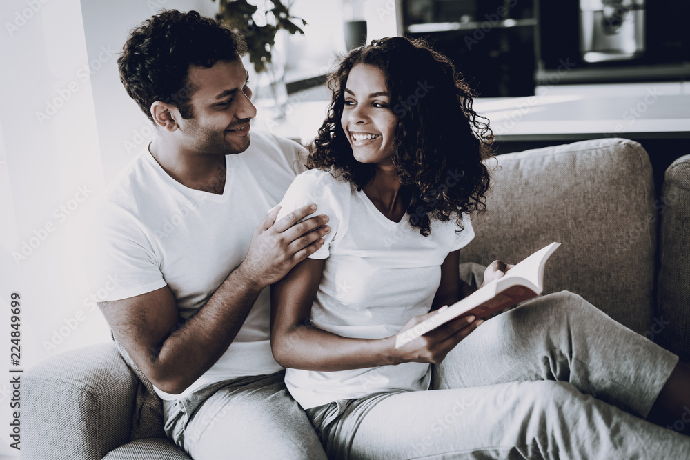 Man Is Hanging Book Reading Girlfriend On Couch. Man Is Hanging Book Reading Girlfriend On Couch.