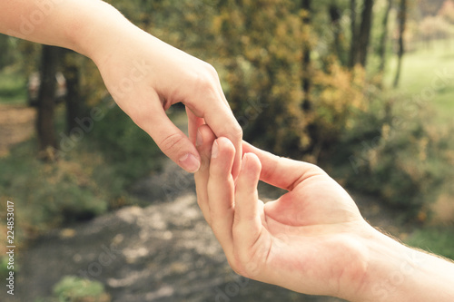 Mans hand gently holding the female against the background of the spring stream, concept of love and Valentine day