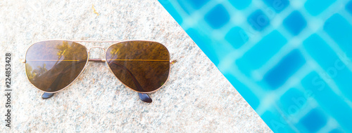 Overhead view of fashion sunglasses and poolside. Summer holiday concept. Banner size with copy space. photo