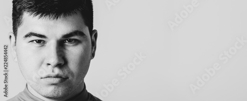 Closeup portrait of serious determined young man. Isolated on grey background with copy space.