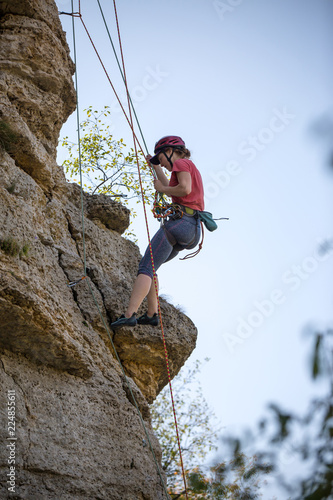Photo of athlete woman in helmet clambering over rock